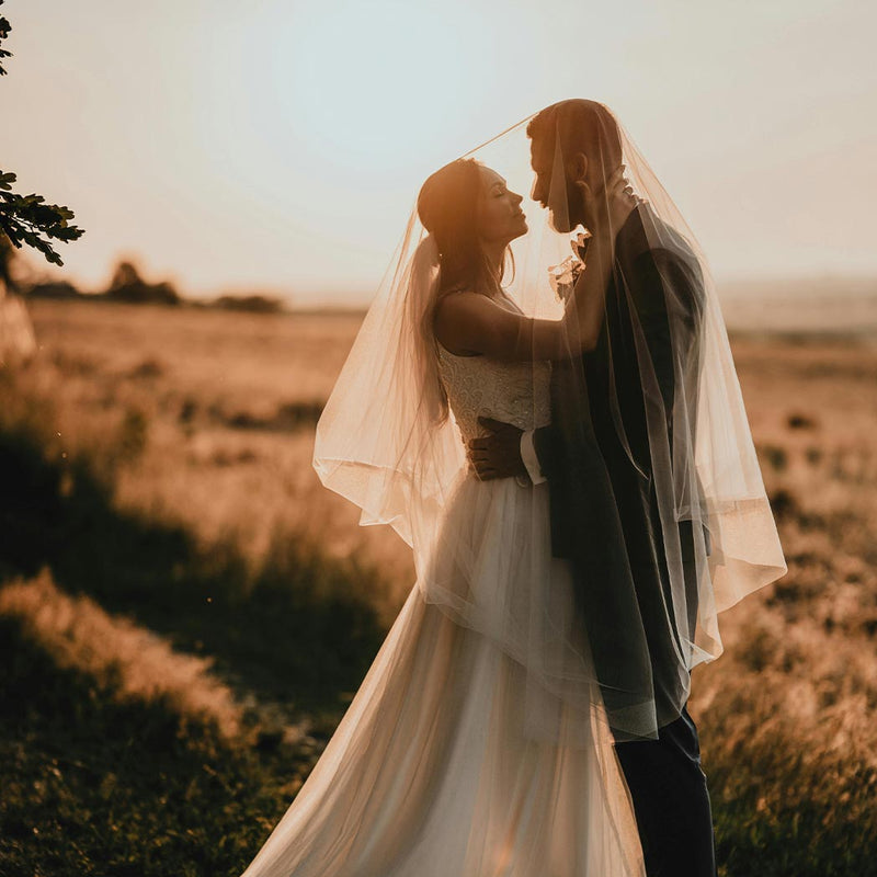 Pareja de novios en su boda mirándose con un paisaje de un campo y de fondo el amanecer