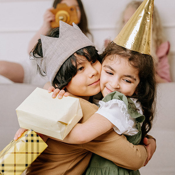 Niños abrazándose mientras que se dan un regalo