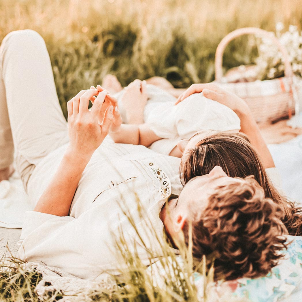 Pareja tumbada en una manta de picnic uniendo sus manos