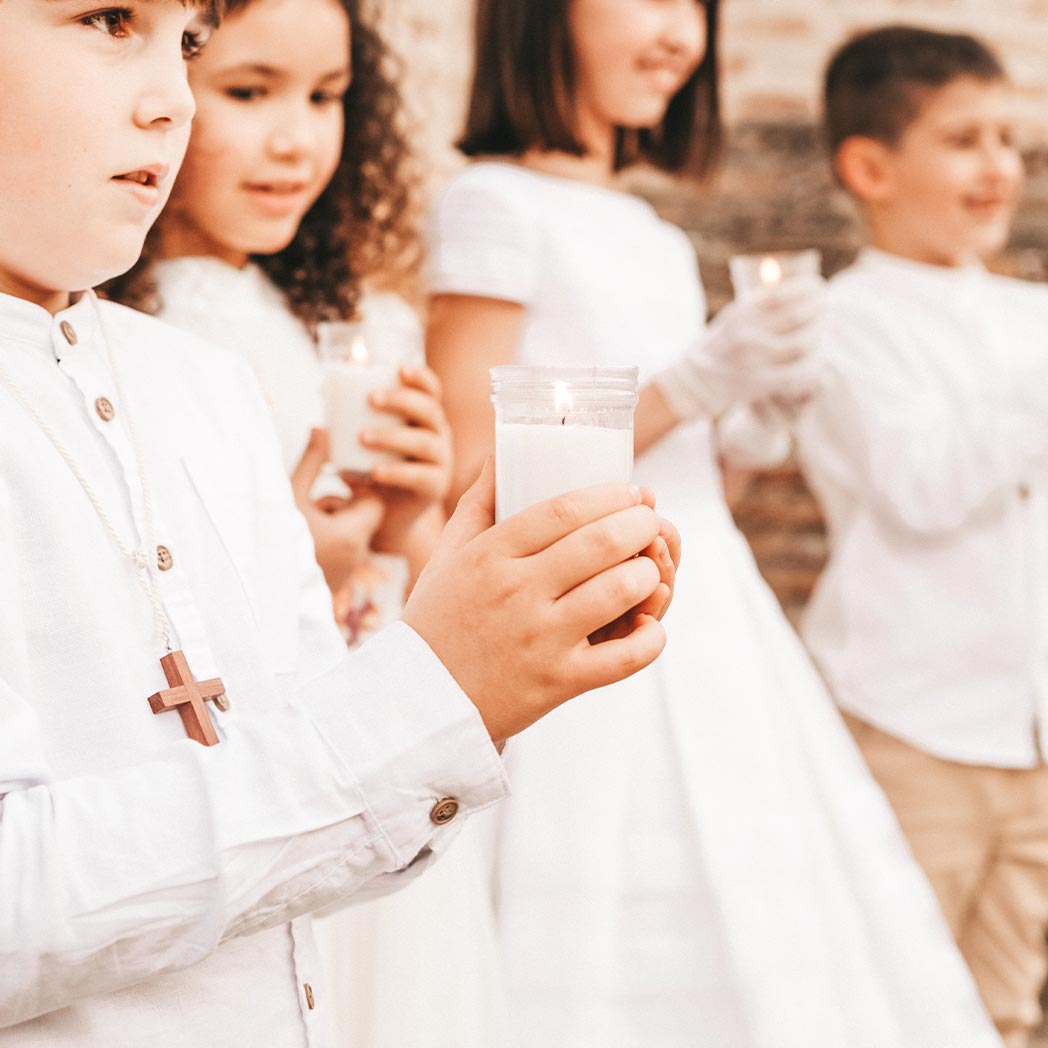 Grupo de niños de comunión sosteniendo una vela