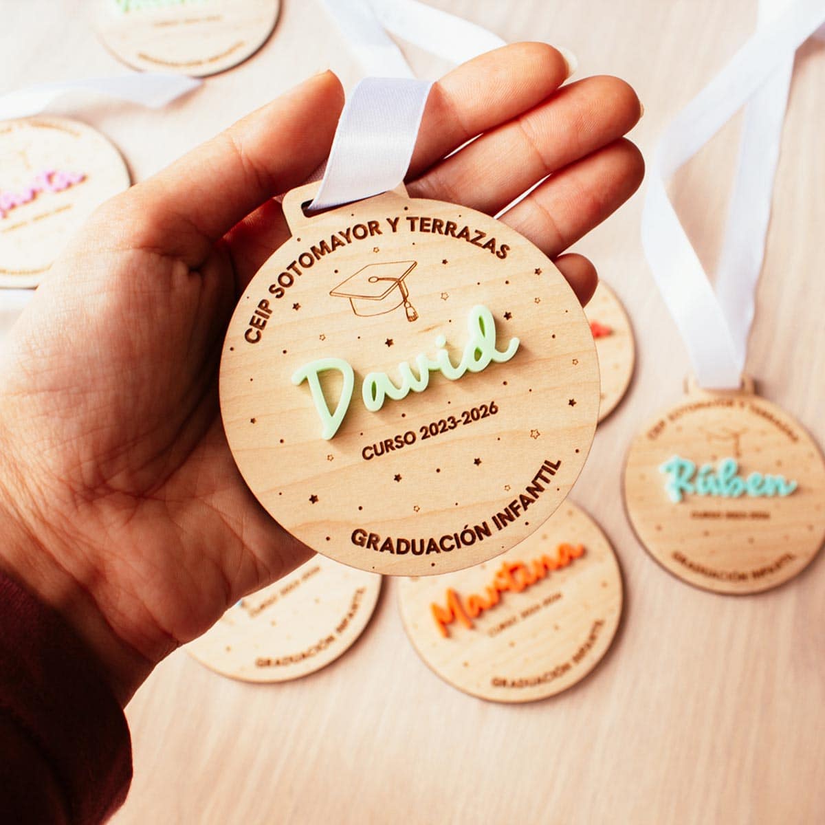 Medalla de graduación de madera sostenida en la mano