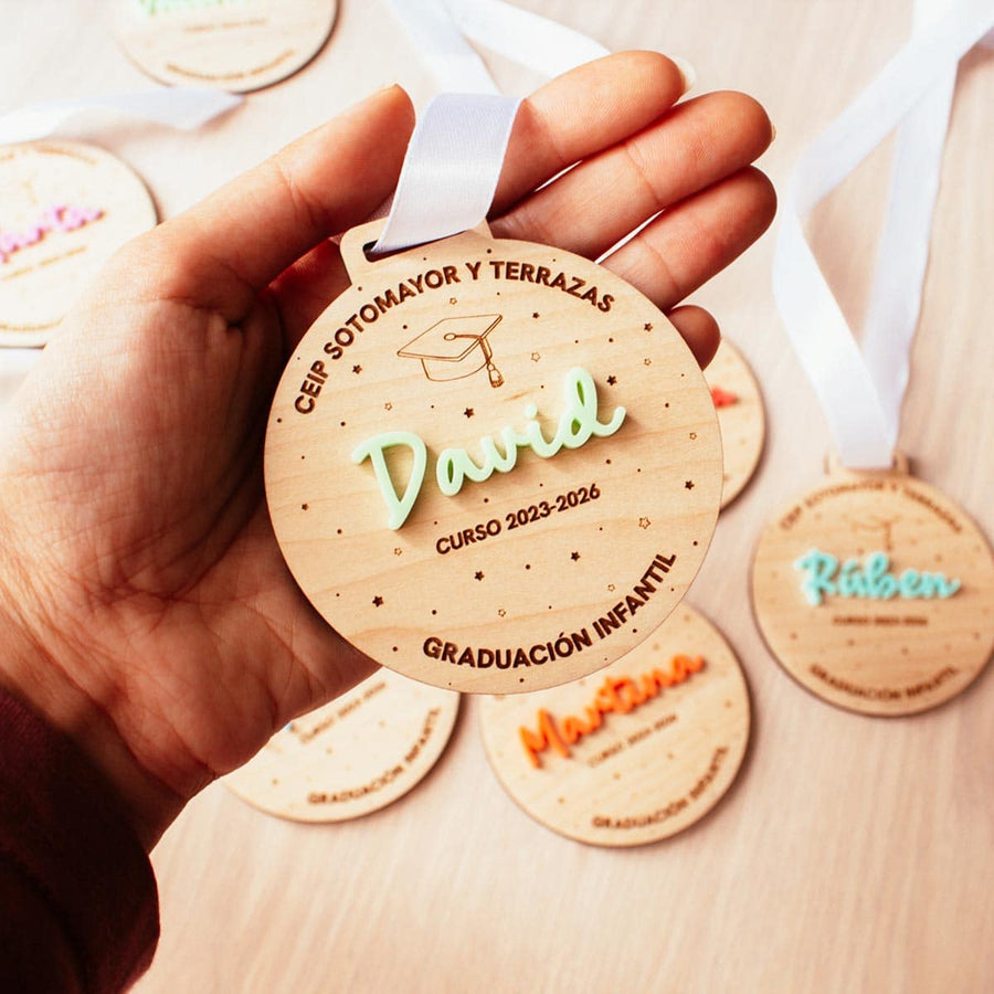 Medalla de graduación de madera sostenida en la mano