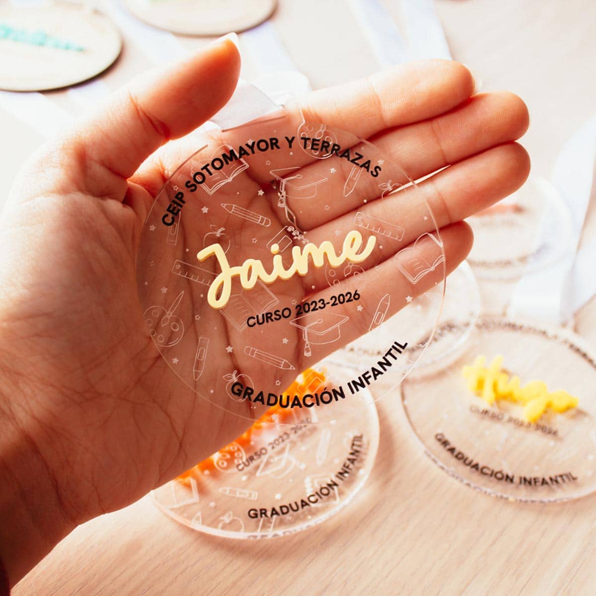 Medalla de graduación metacrilato transparente sostenida en la mano